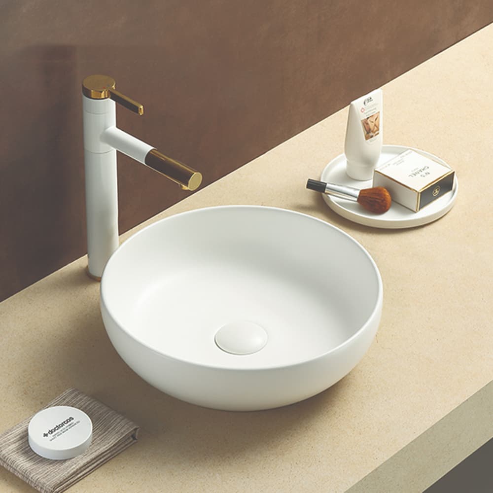 Oban Fine Ceramic Above Counter Basin in Matt White finish with gold faucet on a beige countertop