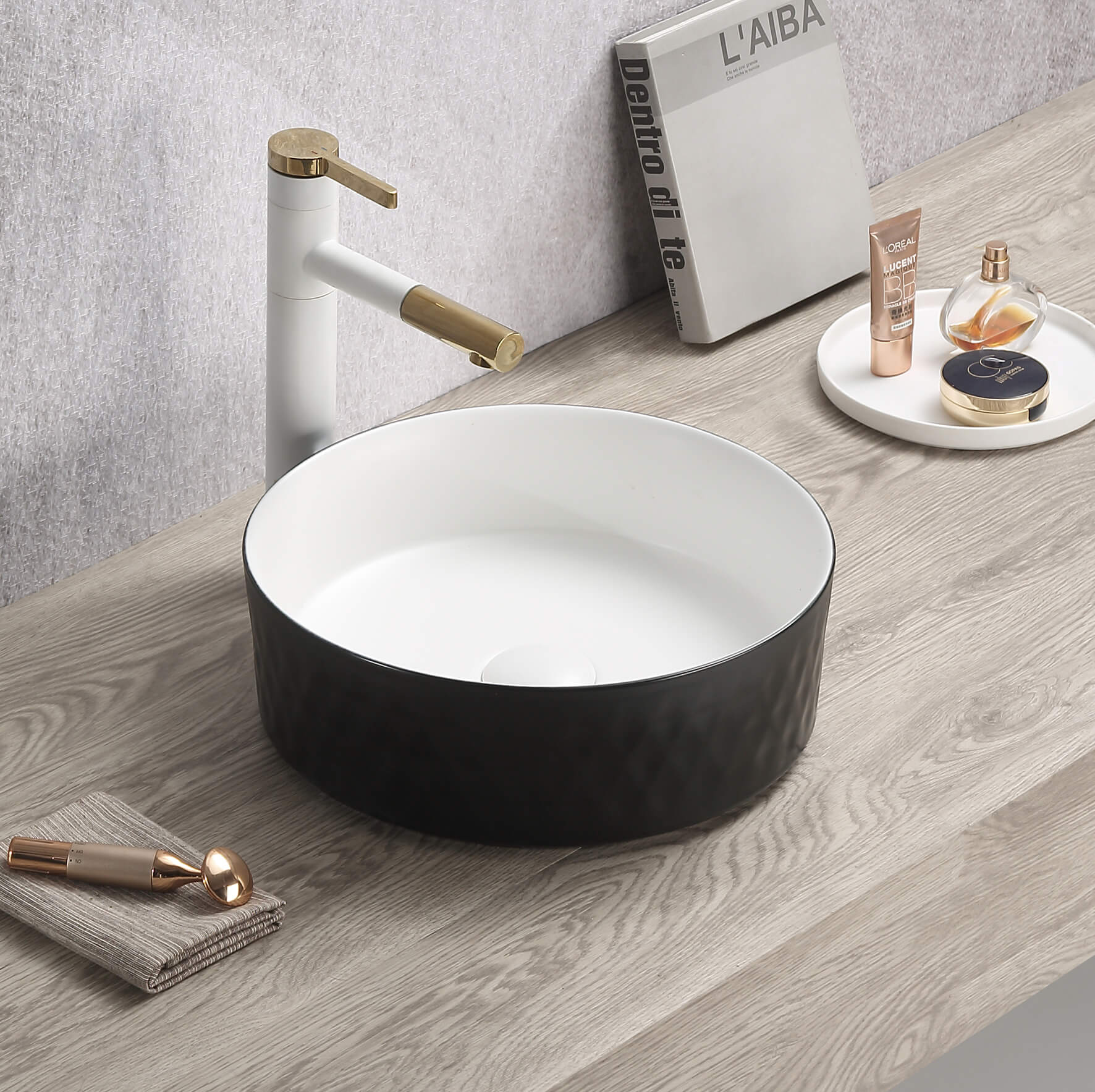 Lukka Ollia Diamond fine ceramic above counter basin in round shape, matte black exterior and matte white interior finish, 360×360×120 mm, non-overflow, 32 mm waste with gold faucet on a wooden countertop