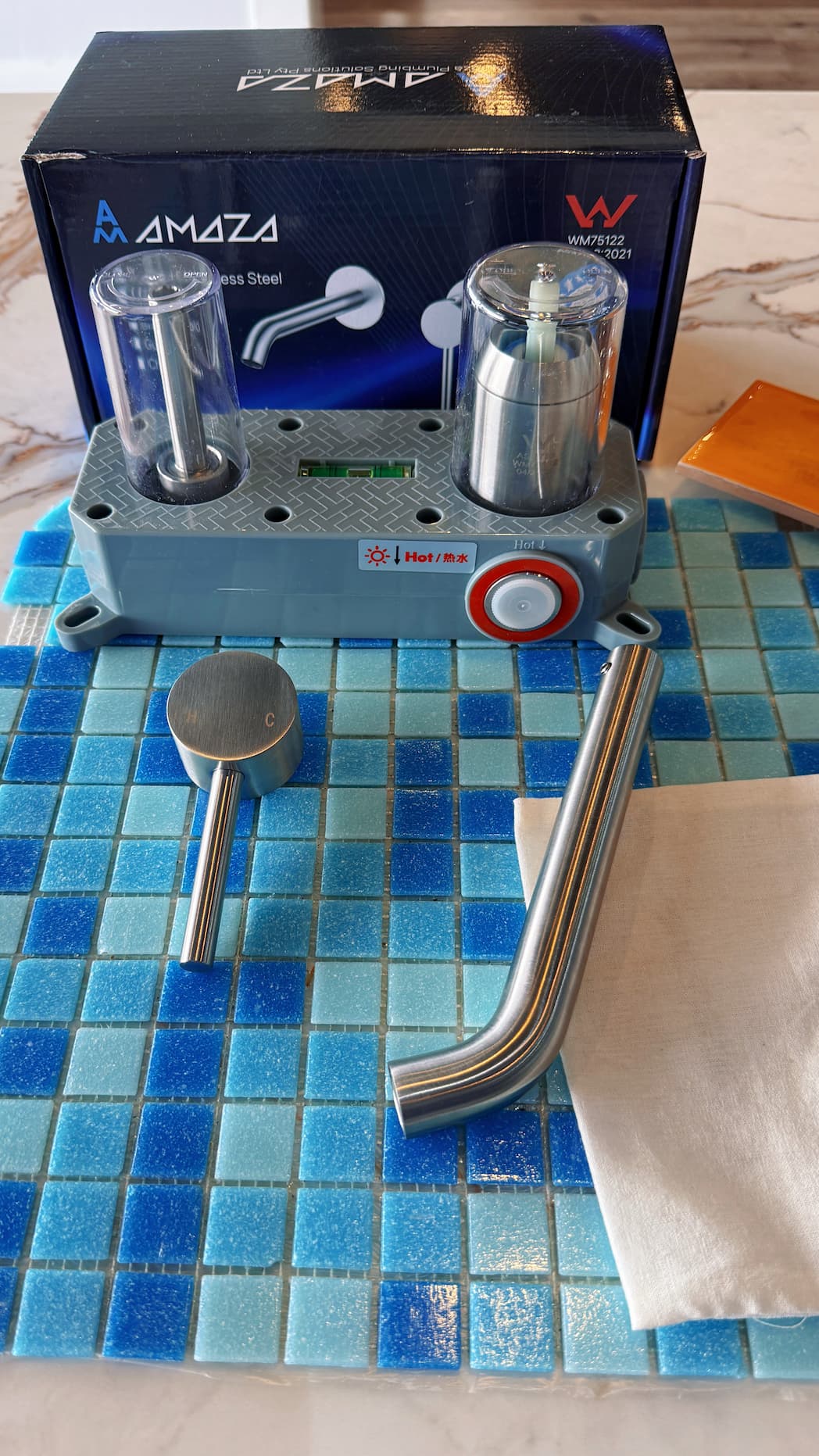 Amoza WM75122 Wall Mounted Basin/Bath Mixer Unboxing. Showing all components: 304 Stainless Steel curved spout, pin lever handle, and grey installation box with 'Hot/Warm' markings.