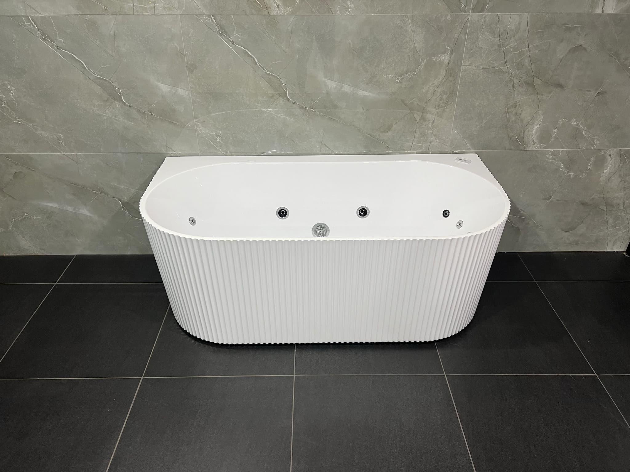 Modern fluted white back-to-wall freestanding bath with jets on dark tile floor, Secasa Home
