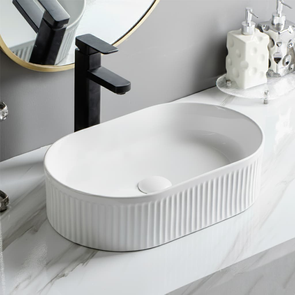 Lukka Ellips Fluted Fine Ceramic Above Counter Basin in oval shape matt black with black faucet in a bathroom setting