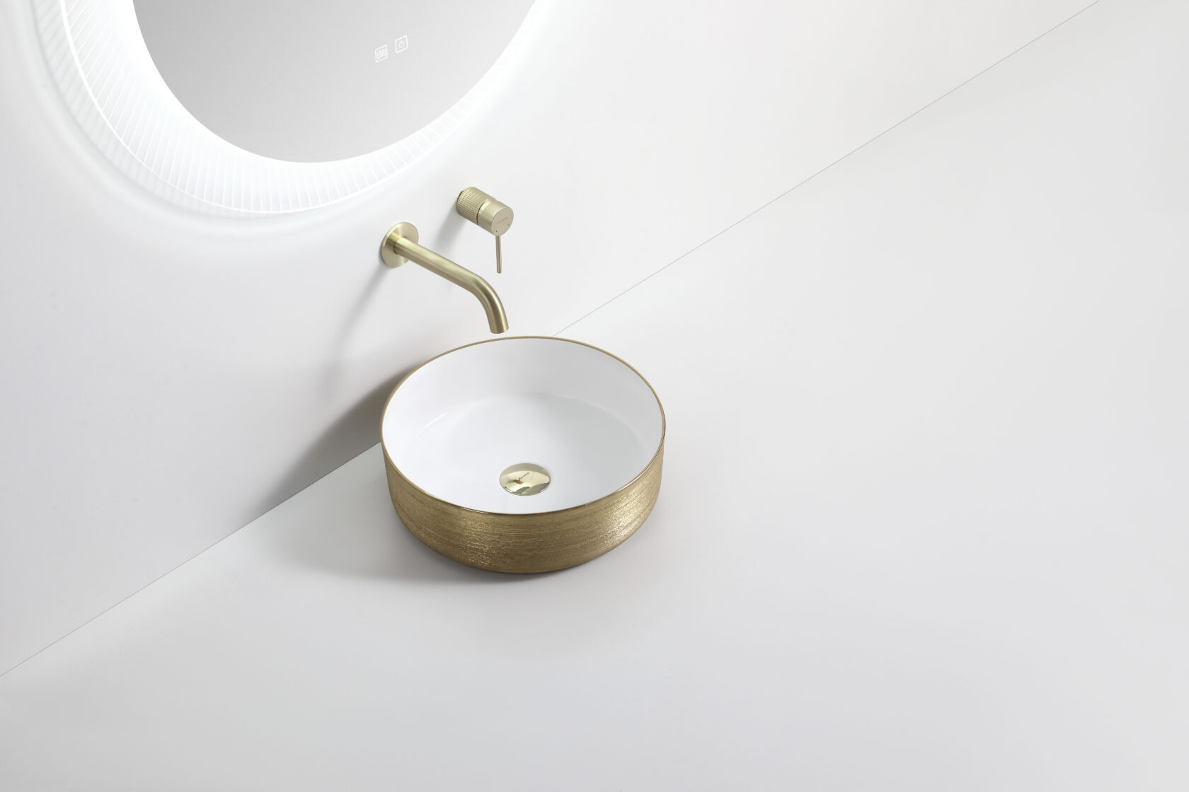 Modern round gold and white bathroom basin with wall-mounted brass tap under backlit mirror