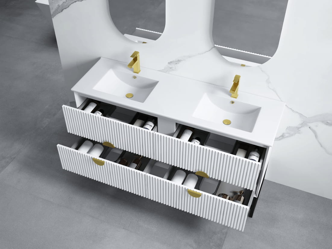 Modern white bathroom vanity with four open drawers, gold taps, double sinks, and marble wall.
