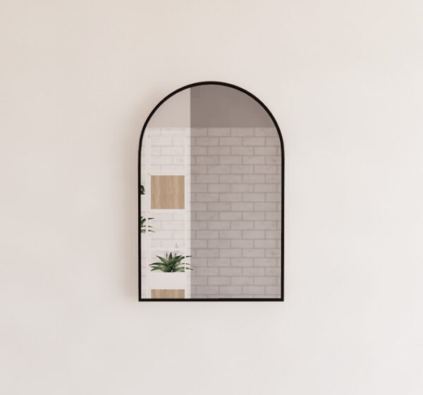 Modern arched bathroom mirror with black frame, brick wall reflection, minimalist decor