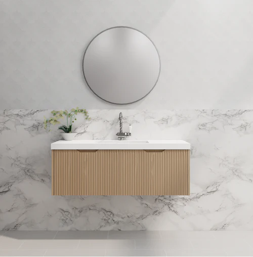 Modern wall-hung bathroom vanity with wood finish, white basin, round mirror, and marble wall
