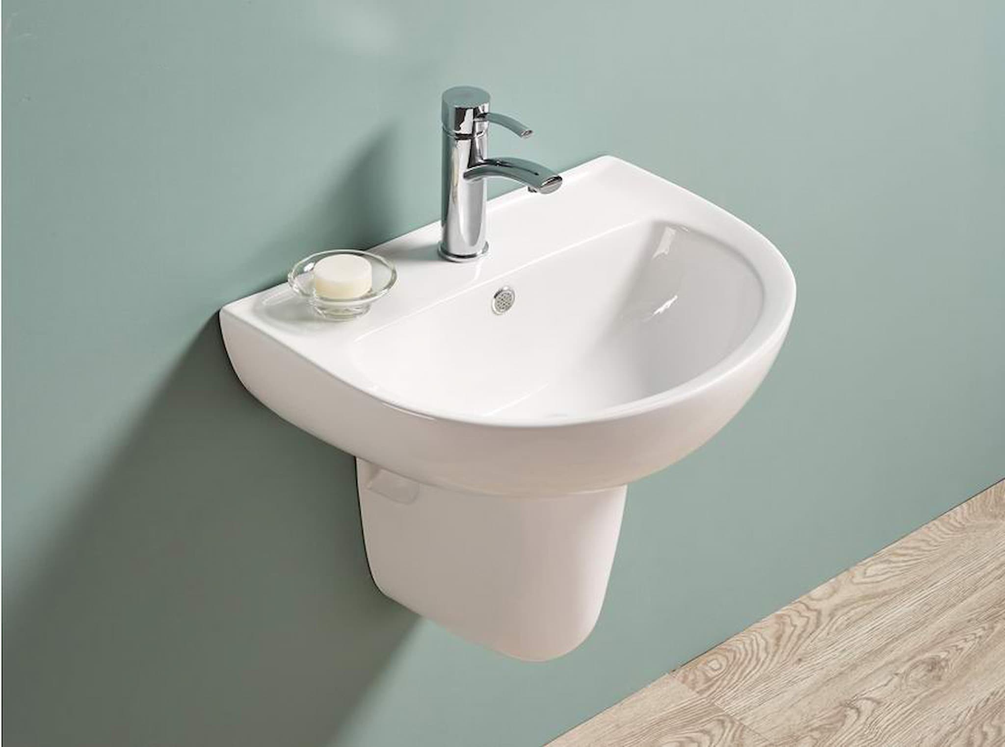 Lukka Carrida Fine Ceramic Wall Hung Care Basin+Pedestal with silver faucet against a light green wall.