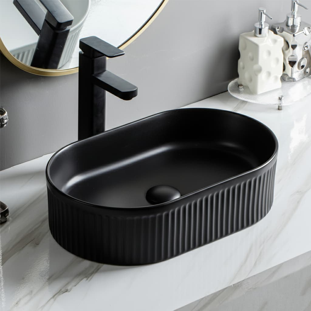 Lukka Ellips Fluted Fine Ceramic Above Counter Basin in oval shape matt black with faucet in a bathroom setting