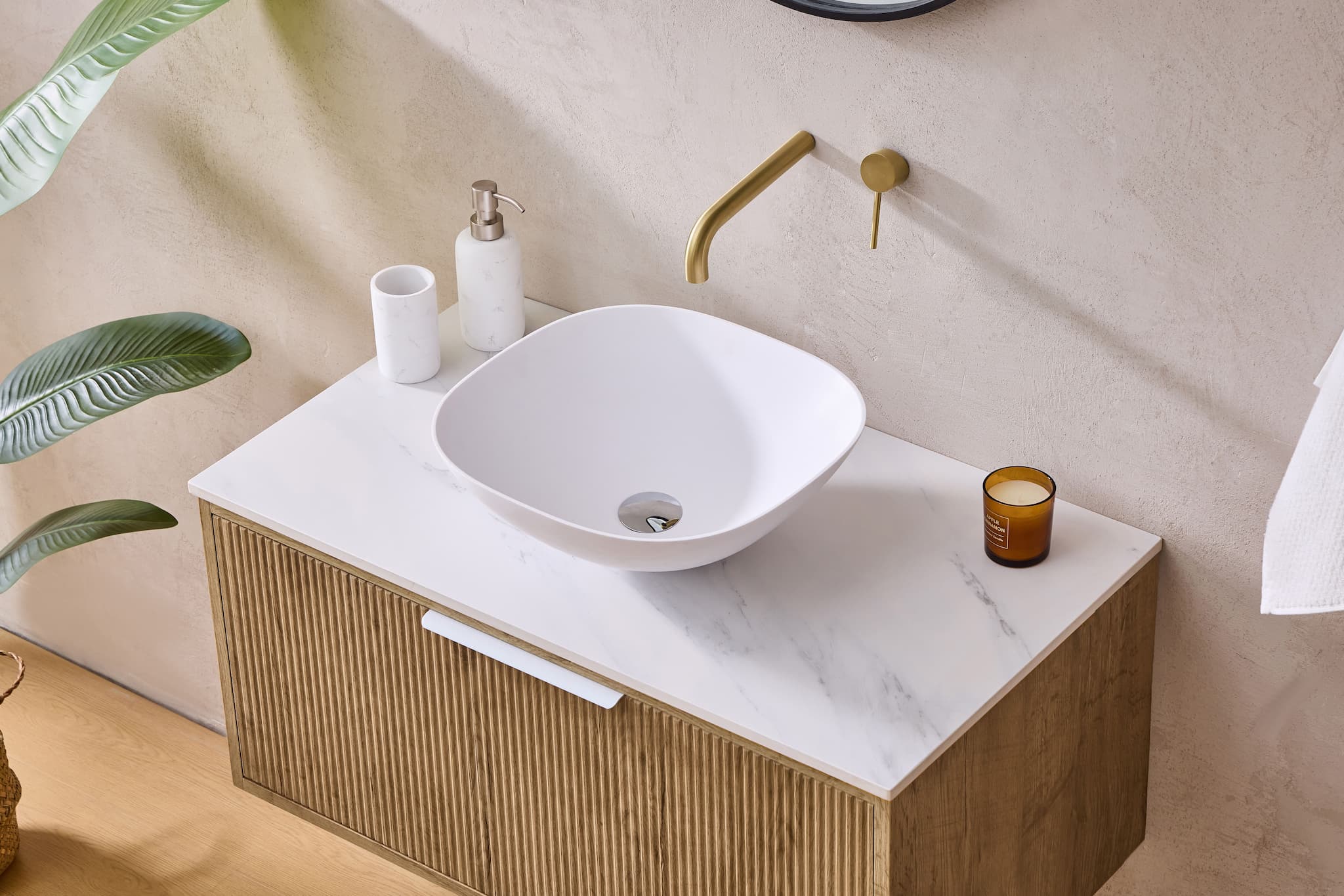 Modern oak bathroom vanity with white marble top, vessel basin, and gold tapware