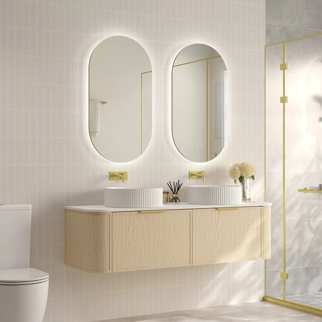Side-angled view of Mercio Elva 1490mm Curved Wall-Hung Vanity in Natural Oak, illustrating its seamless wall-hung installation, graceful curved profile, and harmony with a gold-framed shower screen in a modern bathroom.