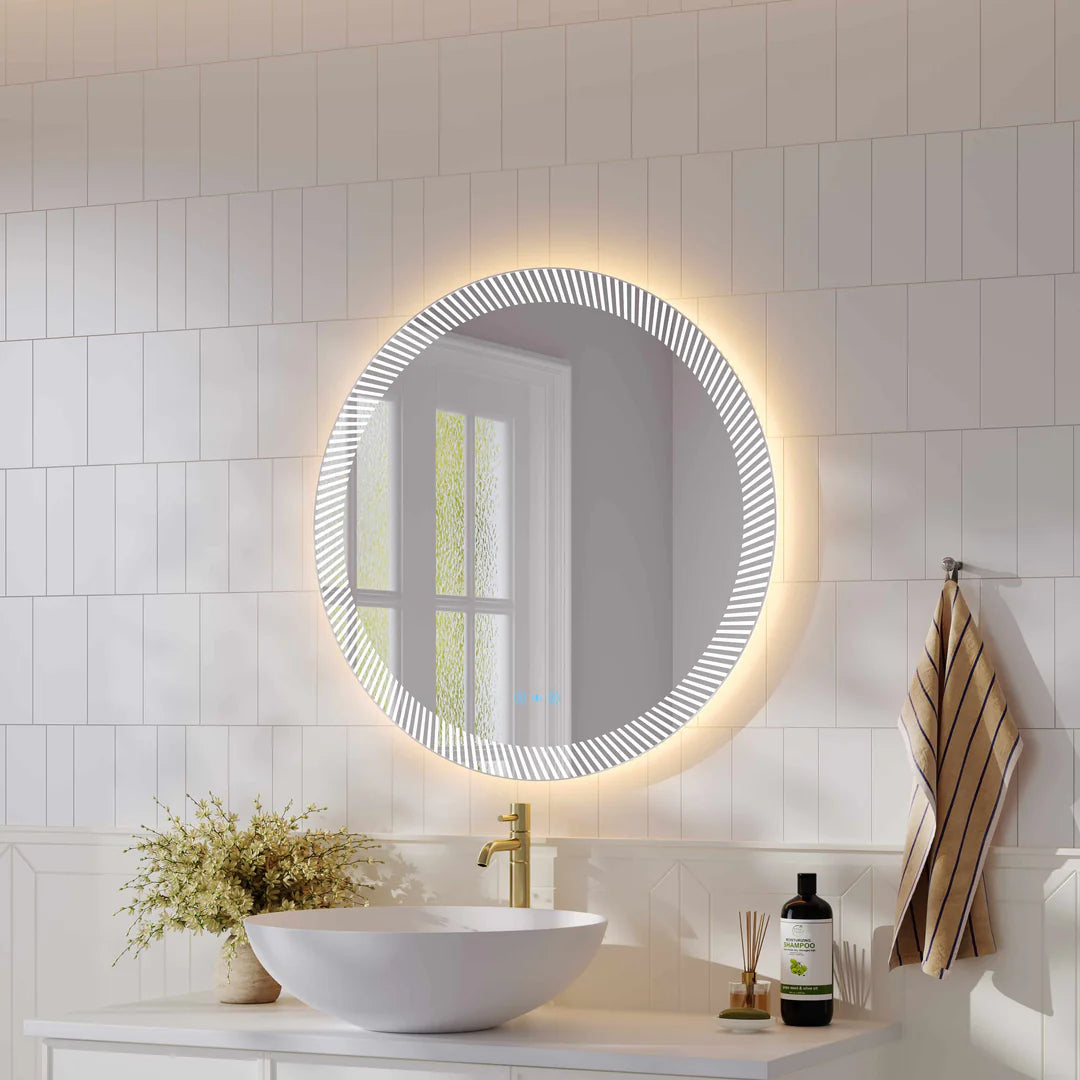 Modern bathroom with round LED backlit mirror above white vanity, gold tap, and indoor plant