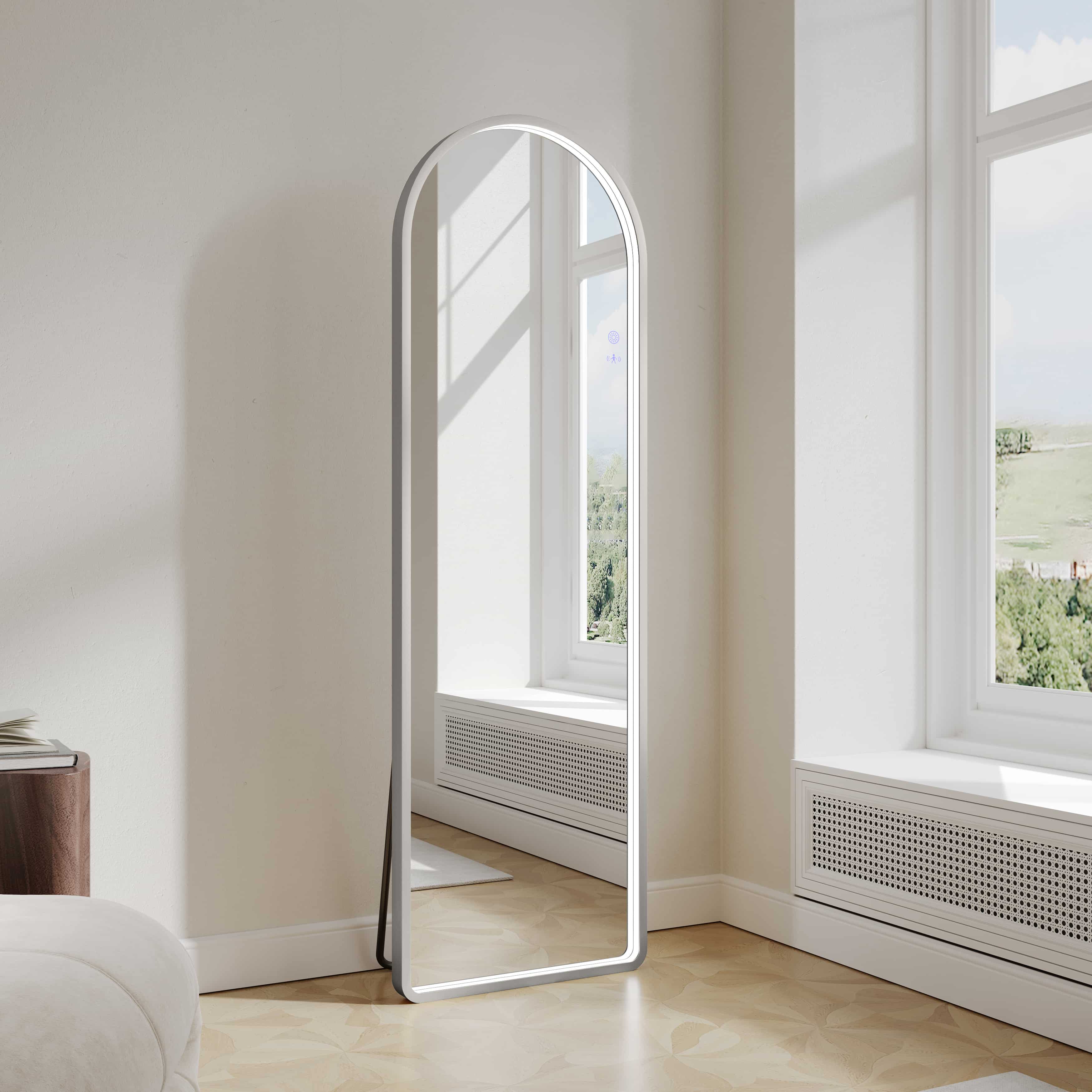 Modern freestanding arch LED mirror with brushed nickel frame in bright minimalist room