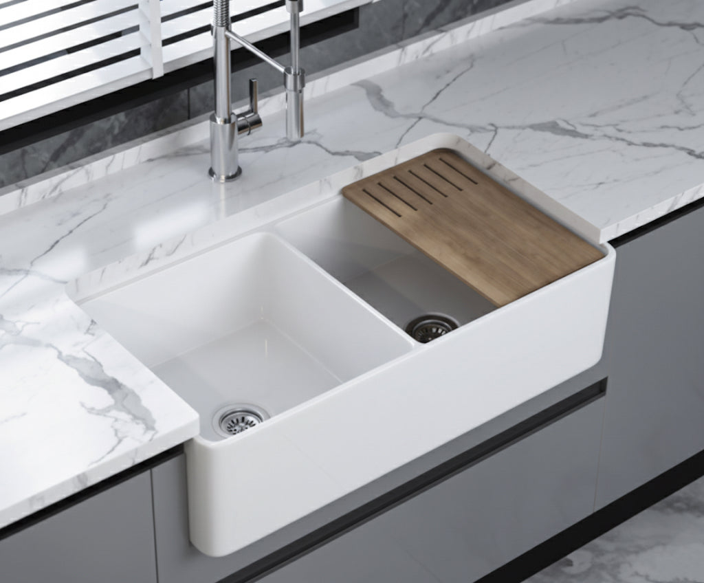 Double bowl farmhouse fireclay sink installed in modern kitchen with bamboo cutting board
