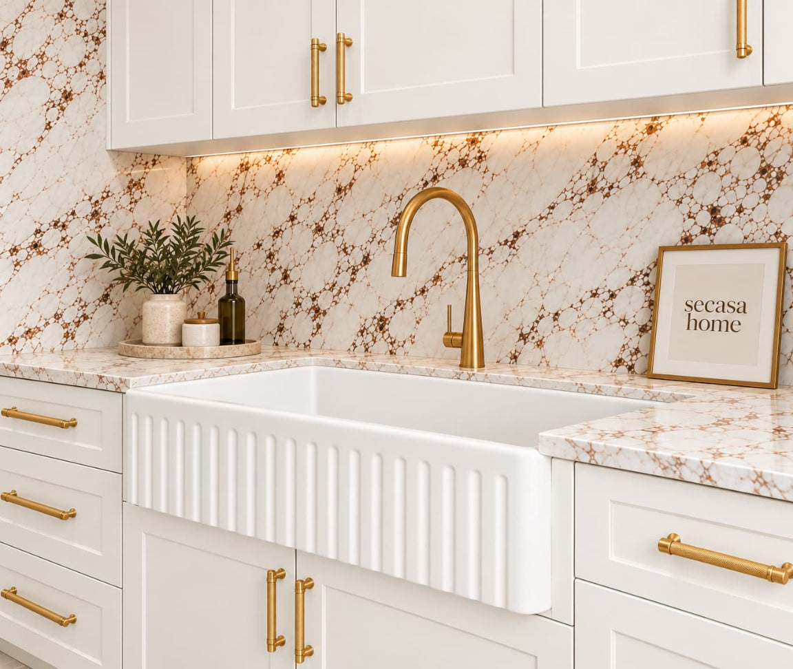 Kitchen scene with white cabinetry, white sink and brass tapware